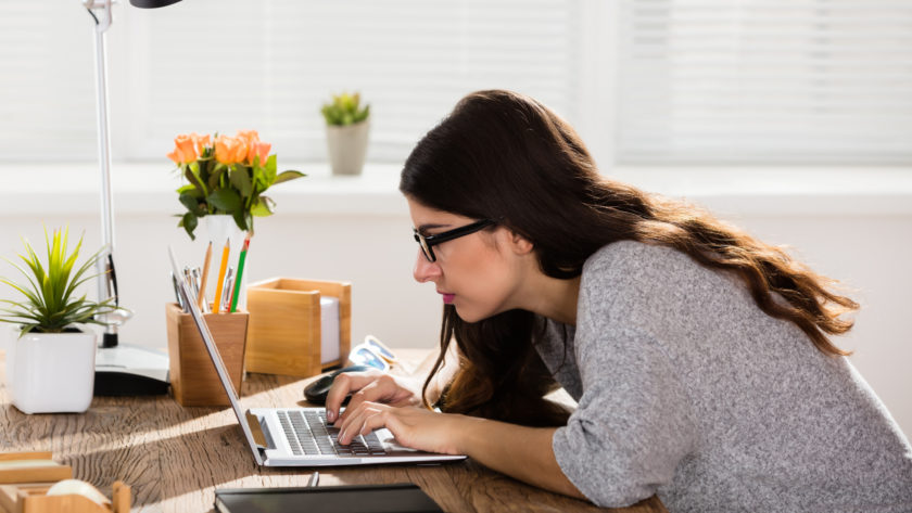 A woman sit uncomfortably in front of a laptop
